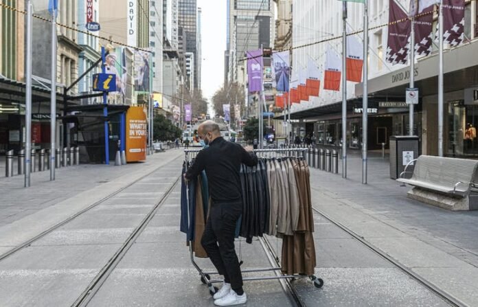 A department store employee wheels clothes across Melbourne’s Bourke Street Mall on August 5 2020, as retailers prepared to close their doors to customers. Asanka Brendon Ratnayake/AP